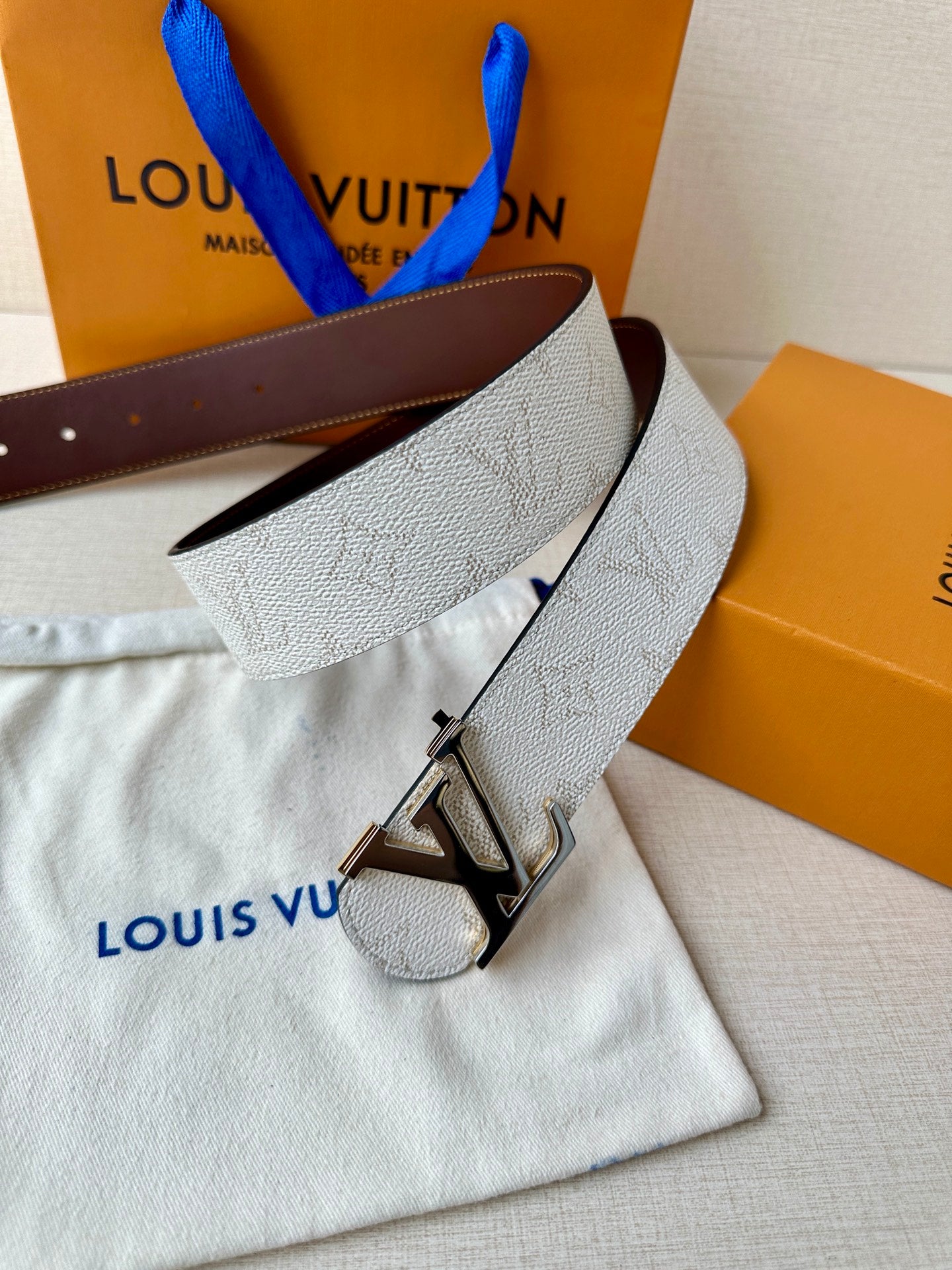 White monogram belt with gold-tone LV buckle and dark brown leather belt end