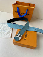 Louis Vuitton belt with blue monogram strap, gold buckle, and black edge laid across box.