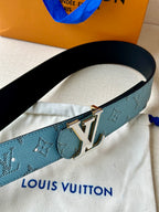 Louis Vuitton belt close-up with blue monogram strap and gold LV buckle on light fabric.