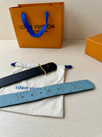 Louis Vuitton belt flat on dust bag, blue monogram strap with gold LV buckle and black edge.