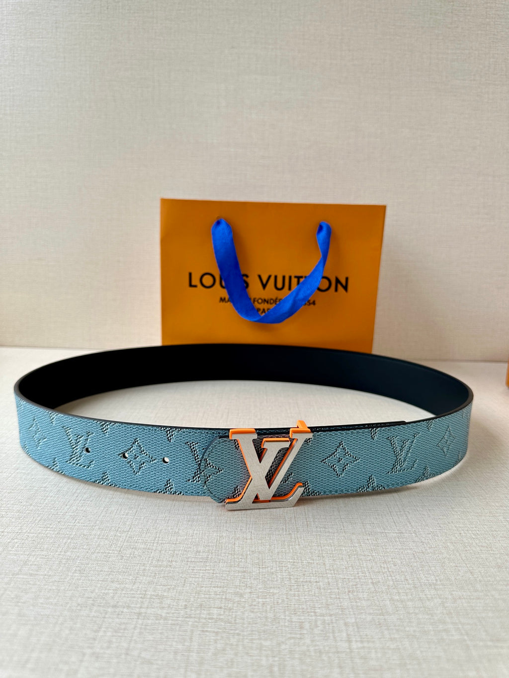 Light blue monogram belt with dark buckle and LV logo centerpiece