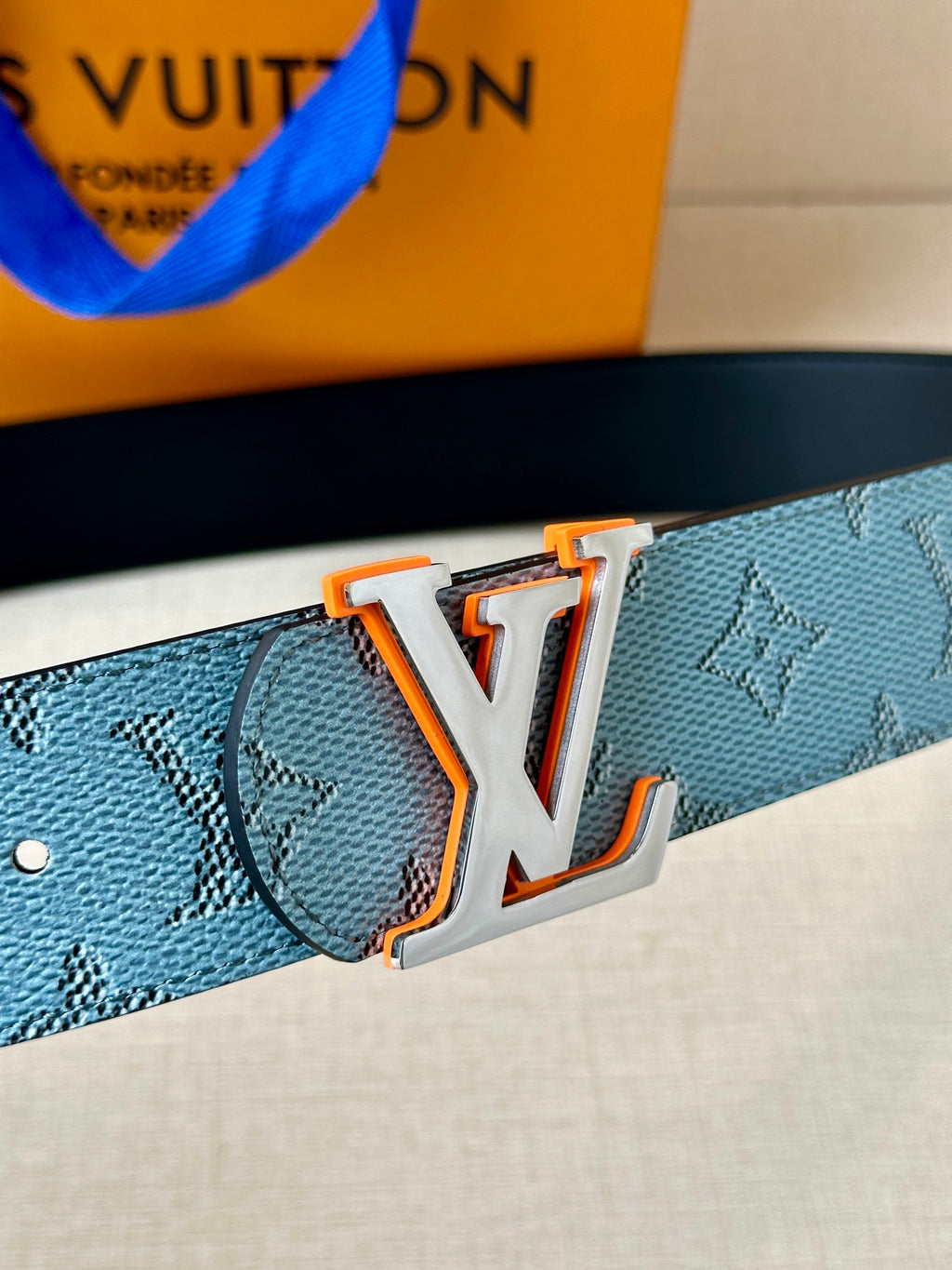 Light blue monogram belt with large LV logo buckle and metal orange trim