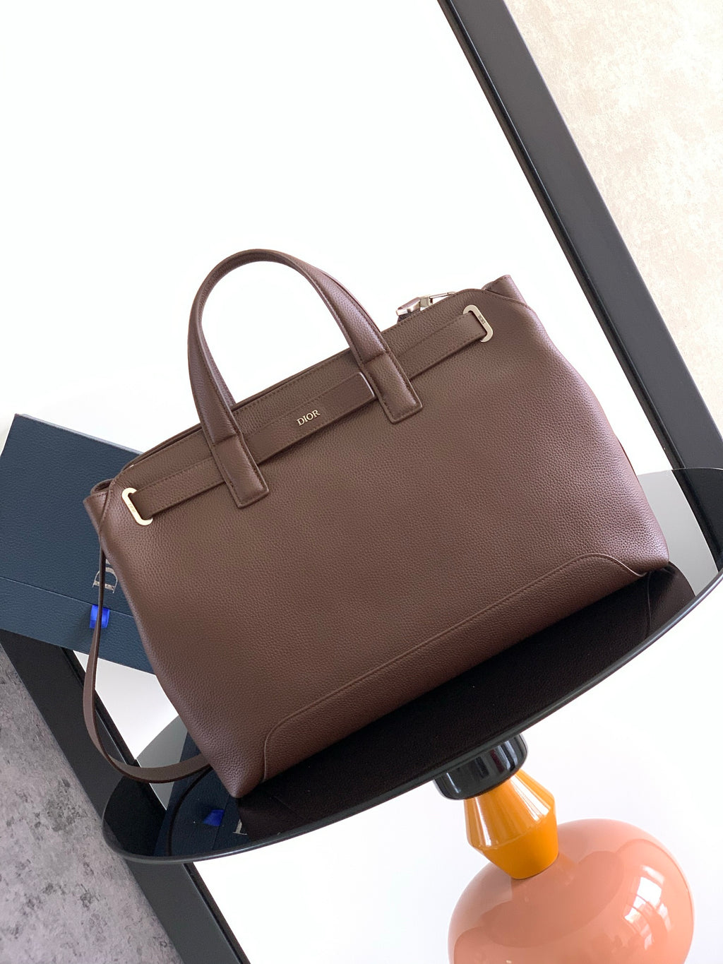 Brown leather tote bag with top handles and front logo patch