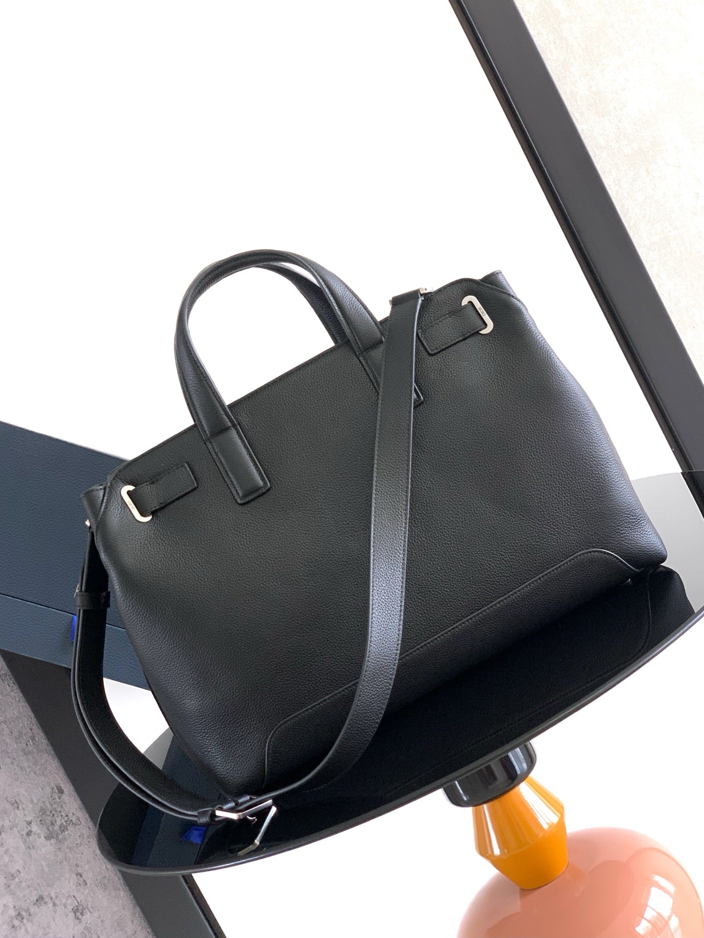 Dior men’s dark leather tote with long shoulder strap and top handle