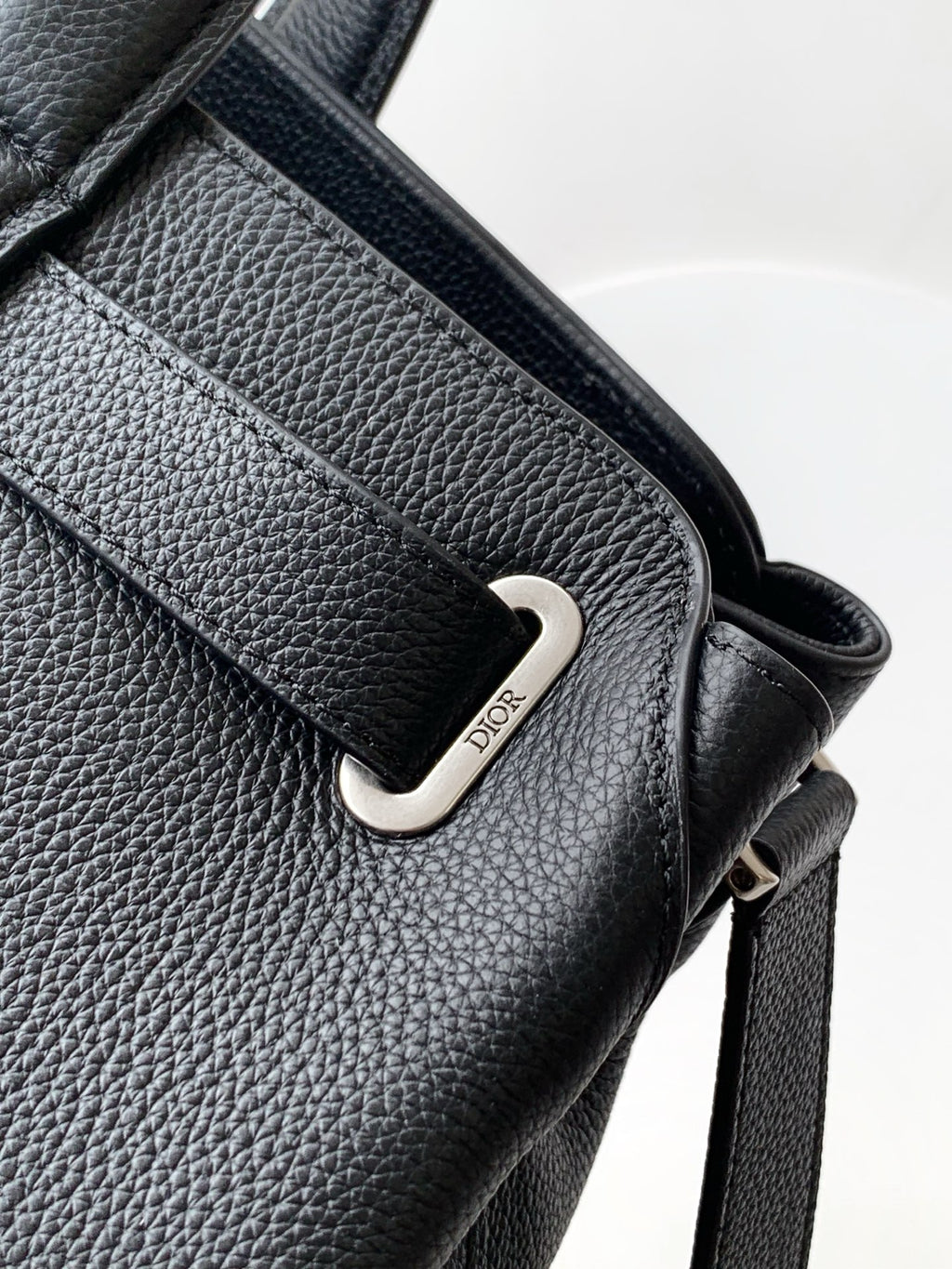 Black leather shoulder strap with silver D-ring buckle and branded snap tab