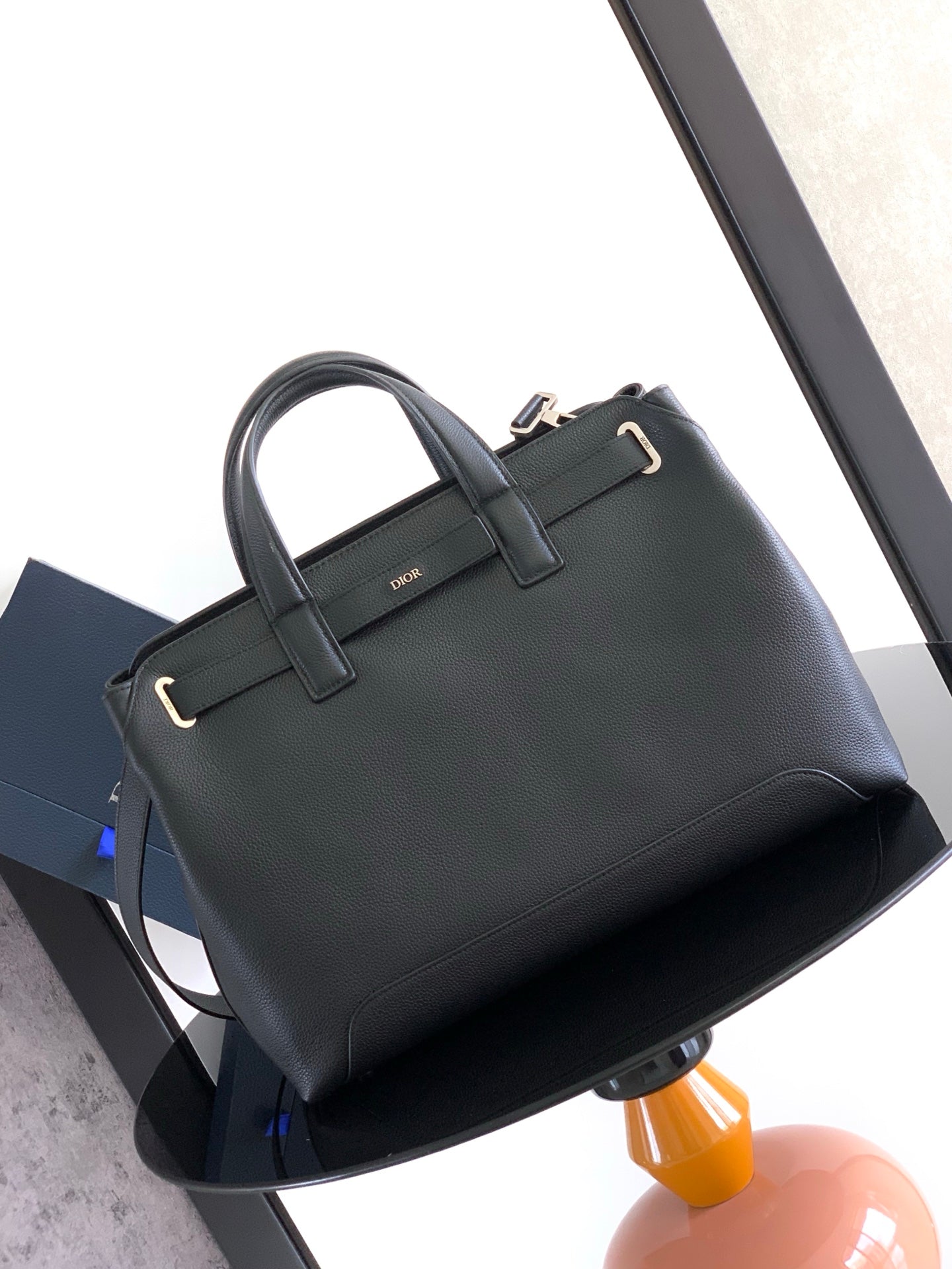 Dior men’s dark leather tote with top handles and front buckle strap