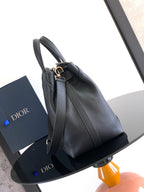 Black leather tote bag with long shoulder strap and metal hardware at top