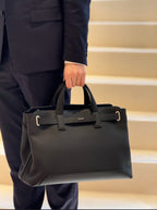 Dior structured tote with top handles and front logo, held by handles