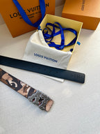 Camo belt with gold-tone buckle and dark leather strap, laid on dust bag