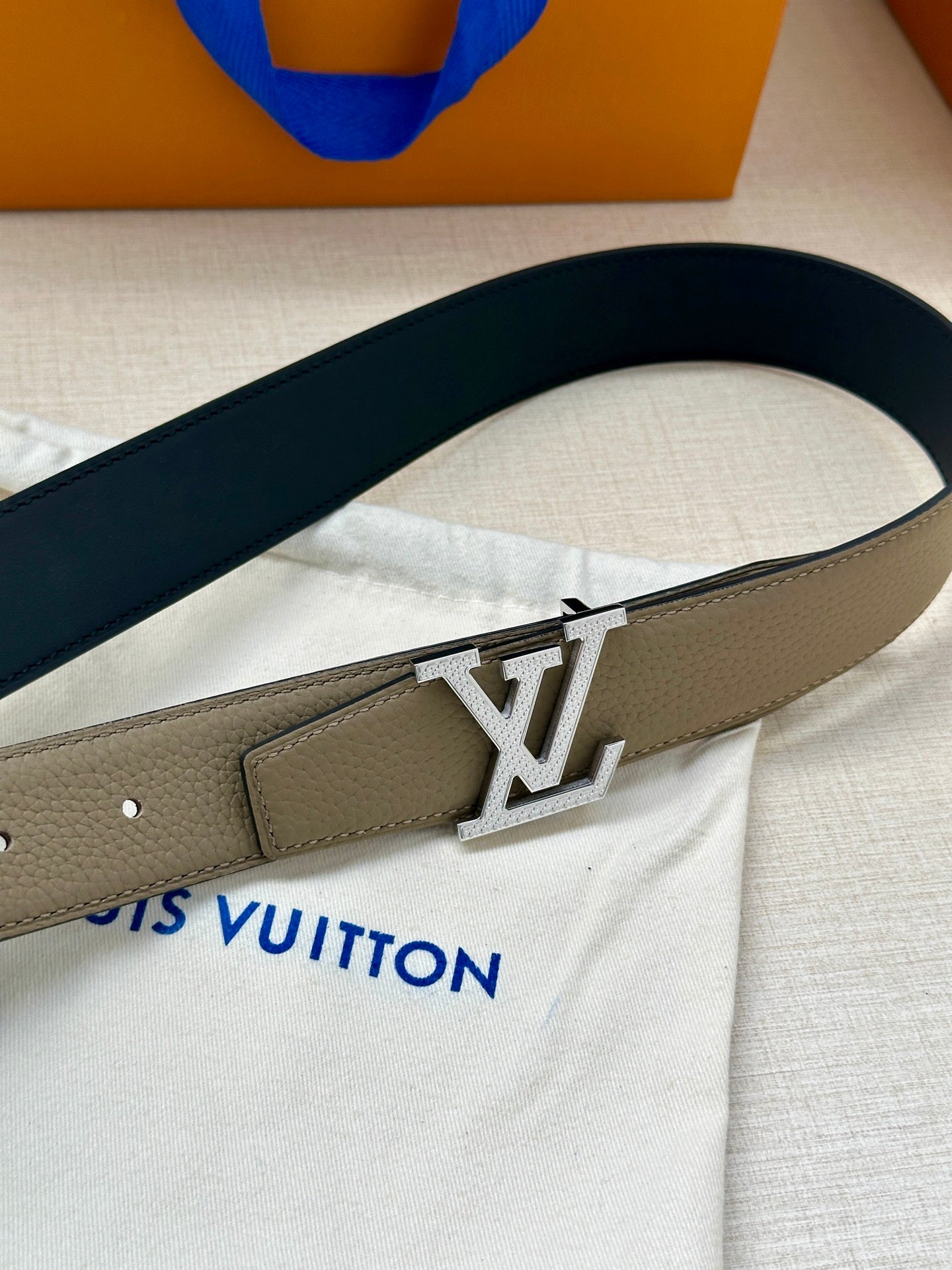 Louis Vuitton belt close-up: beige leather with gold LV buckle on dark strap