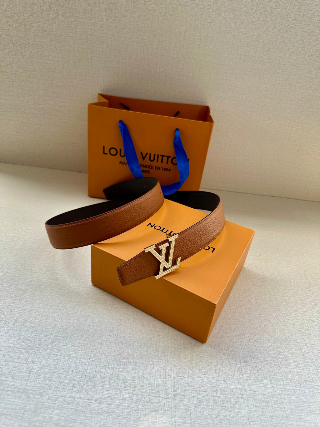 Louis Vuitton belt, brown strap and silver LV buckle on display.