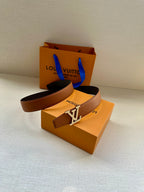 Louis Vuitton belt, brown strap and silver LV buckle on display.