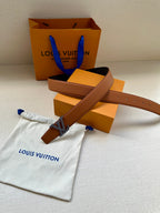 Louis Vuitton belt with brown strap and silver LV buckle, on white dust bag.