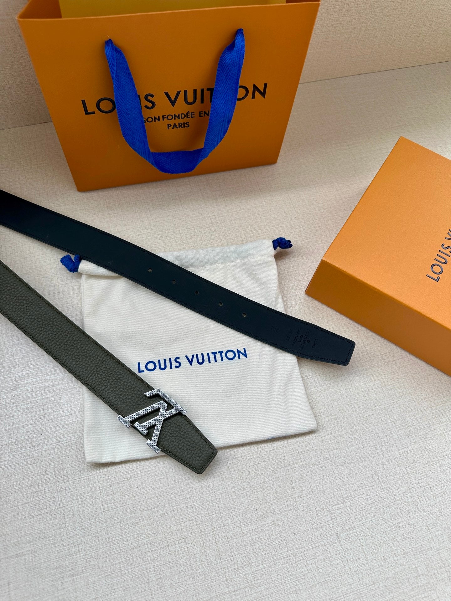 Dark green leather belt with gold LV buckle, laid out