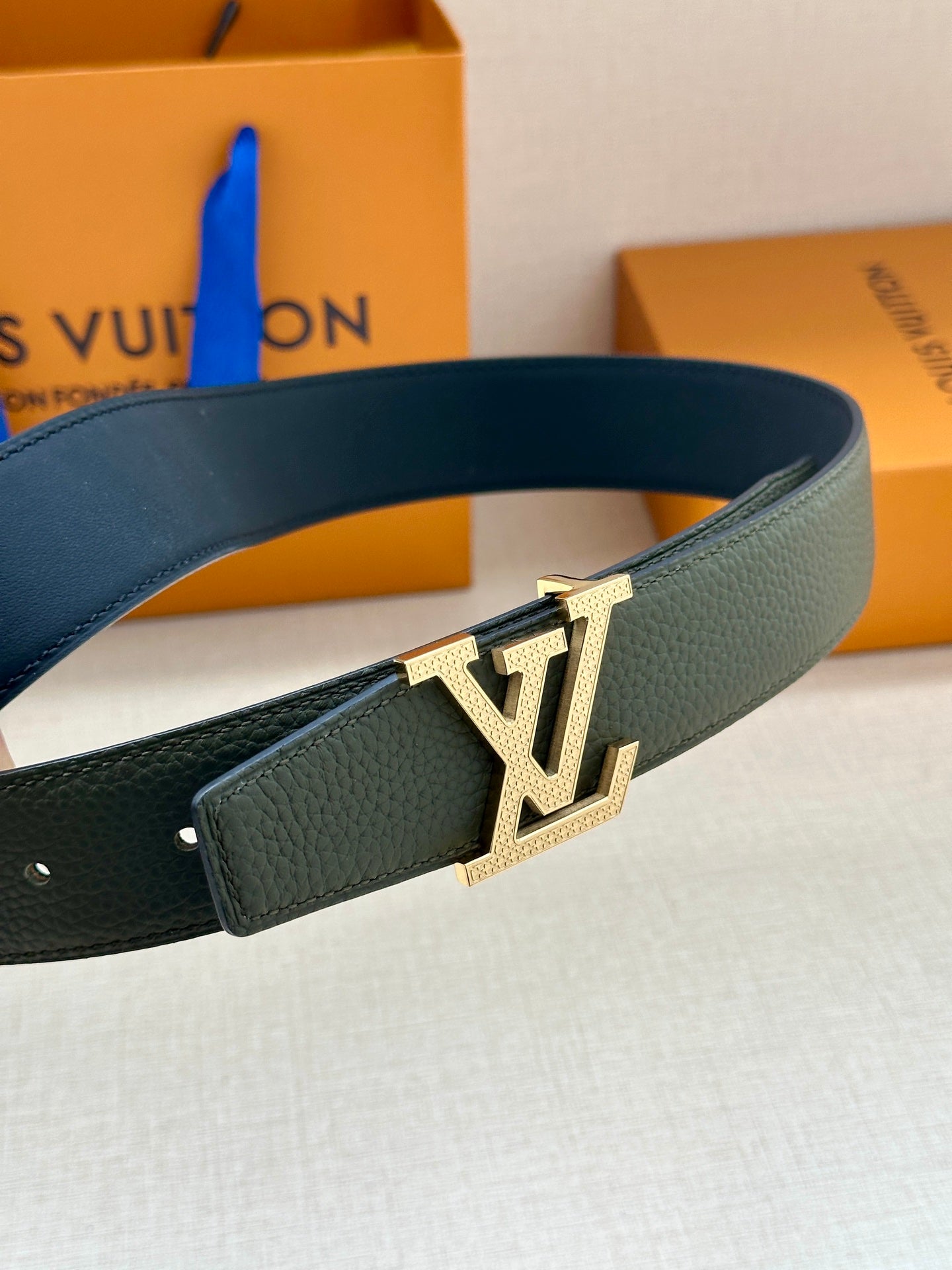 Dark green belt with gold LV logo buckle, angled view