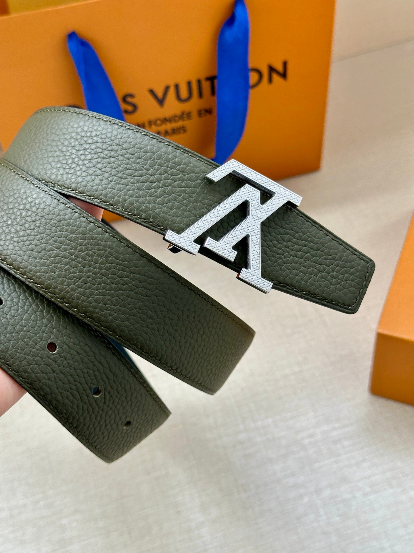 Dark green leather belt with large gold LV buckle on strap