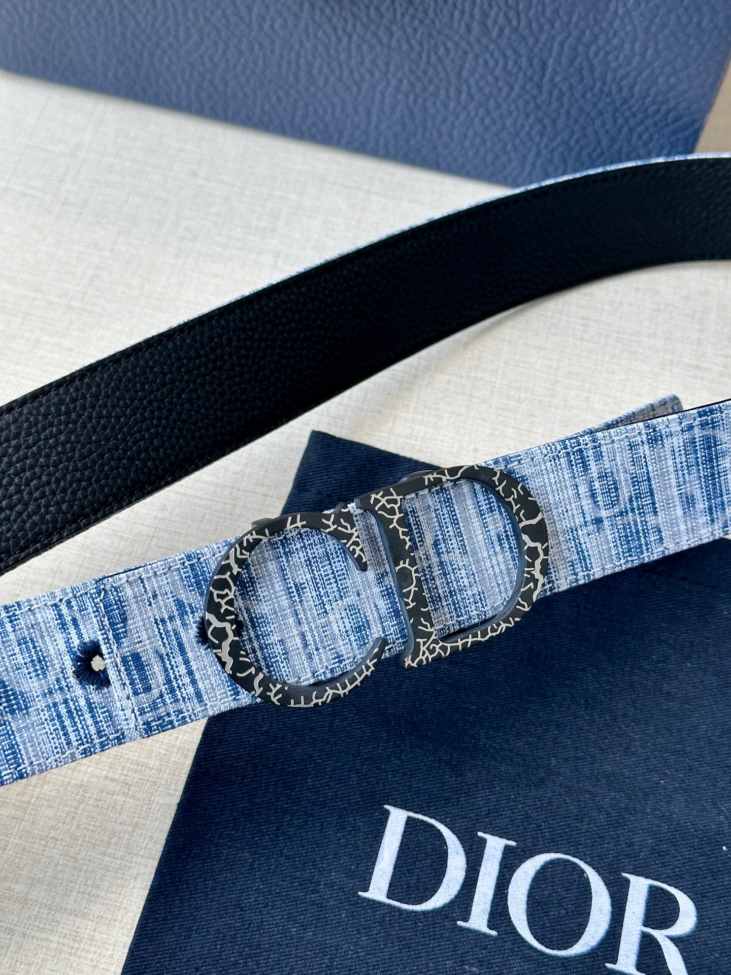 Dior belt close-up with textured blue strap and double circular buckle