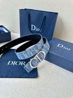 Blue plaid belt with silver CD buckle and visible woven texture on box set.