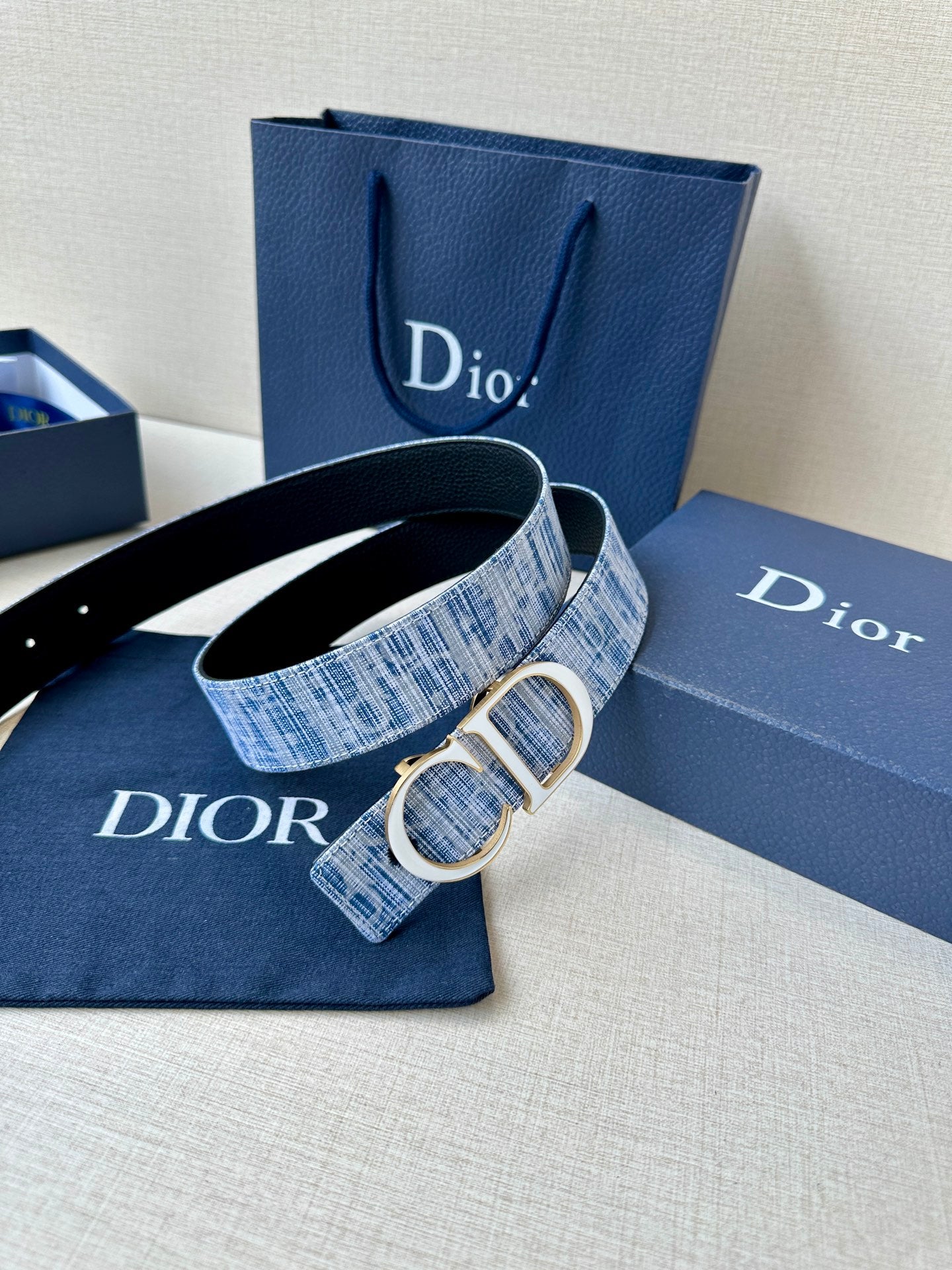 Blue plaid belt with silver CD buckle and visible woven texture on box set.