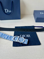 Blue and white woven belt with silver CD buckle, laid flat on navy cloth.