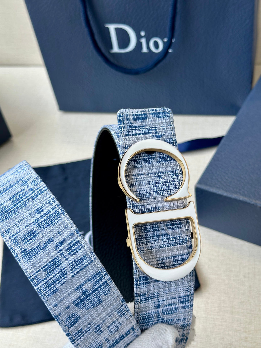 Close-up of blue woven belt loop with silver CD buckle and strap end.