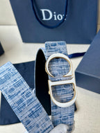 Close-up of blue woven belt loop with silver CD buckle and strap end.