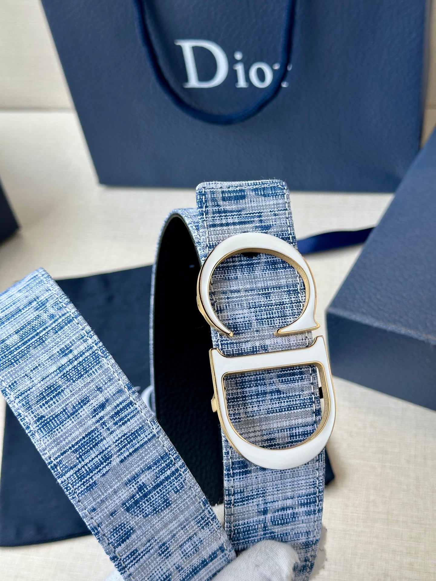 Close-up of blue woven belt loop with silver CD buckle and strap end.