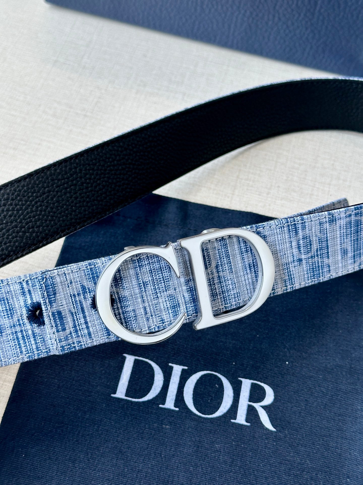 Blue plaid weave belt with silver CD buckle, shown from a side angle.