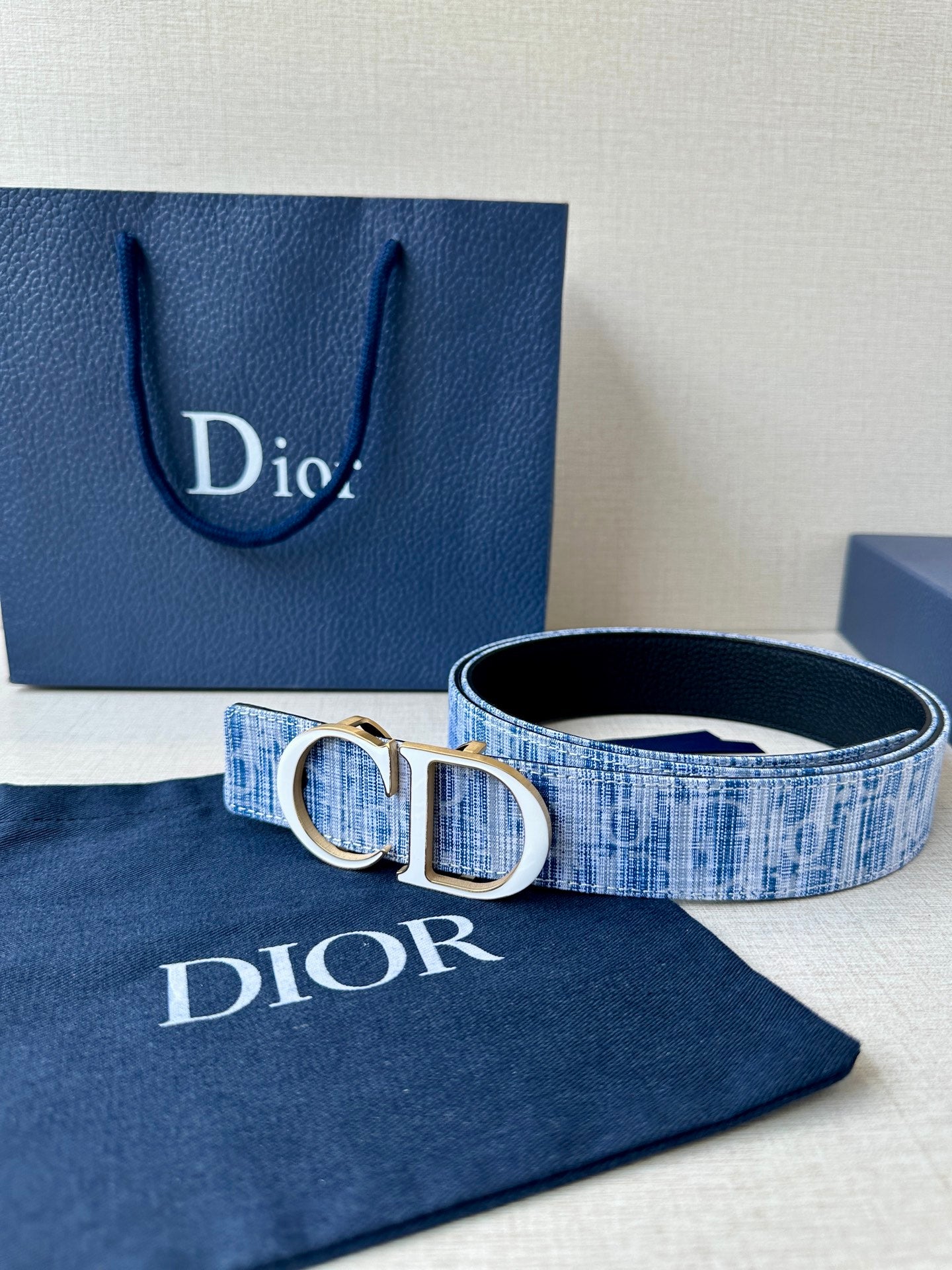 Blue patterned belt with gold-trimmed silver CD buckle and inner black side.
