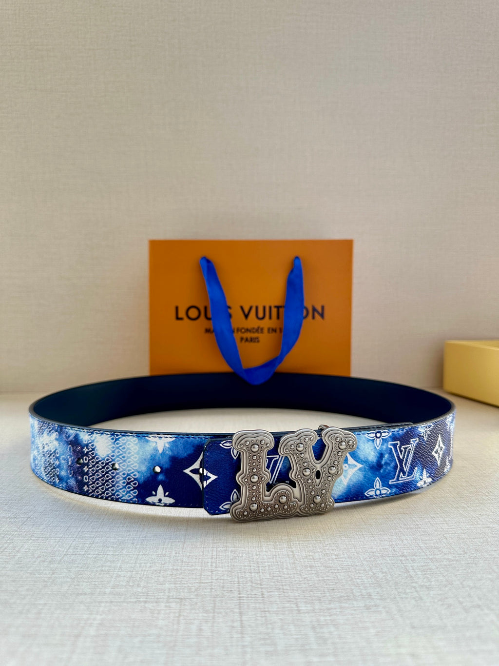 Louis Vuitton belt in blue monogram print with gold-tone ornate buckle detail.