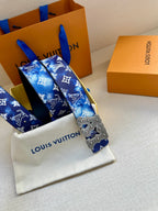 Louis Vuitton belt with blue monogram print and gold-tone ornate buckle on dark strap.