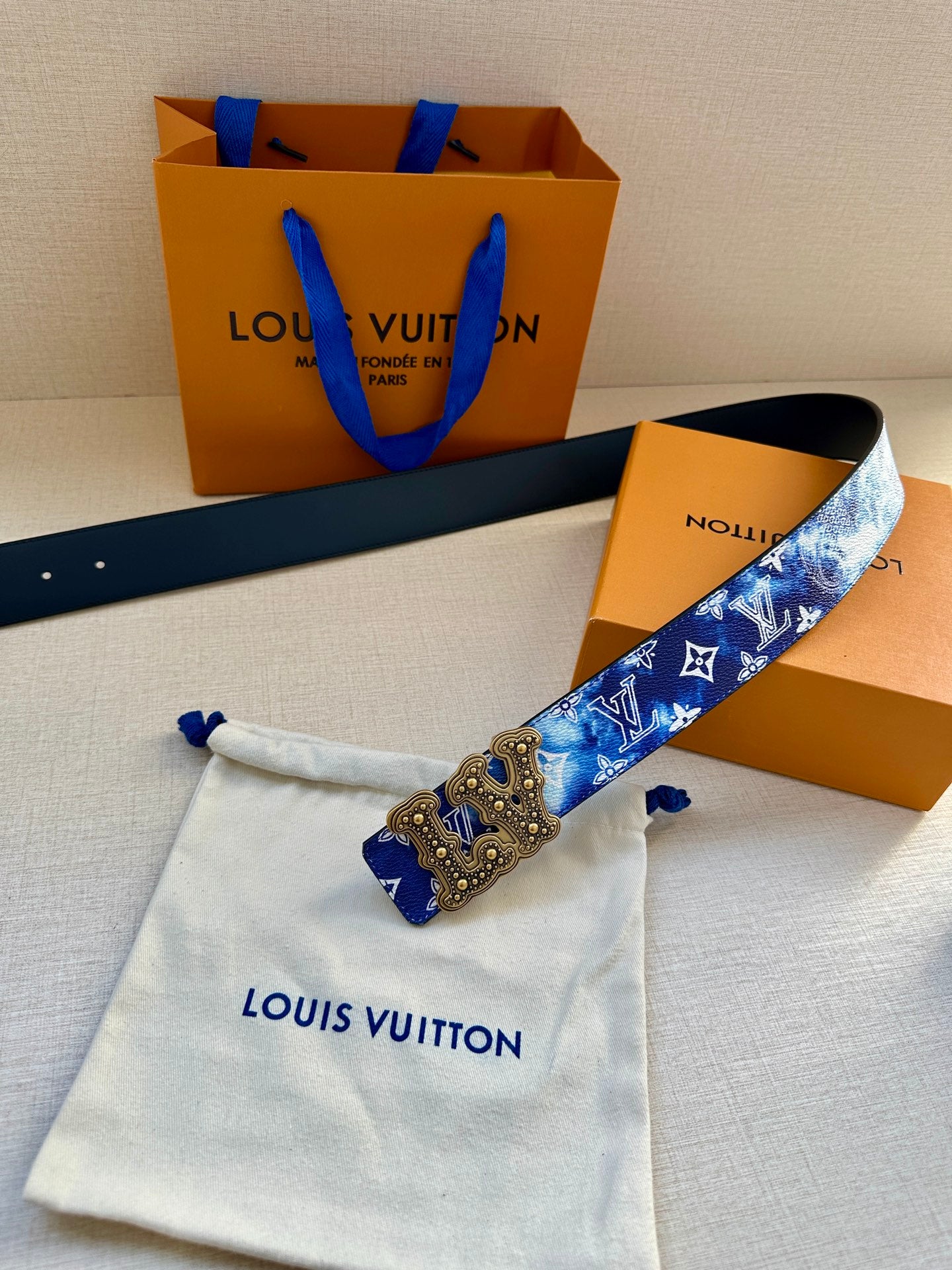 Louis Vuitton belt with blue monogram strap, gold-tone ornate buckle, and black backing.