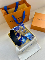 Louis Vuitton belt shown angled: blue monogram strap with gold-tone ornate buckle detail.