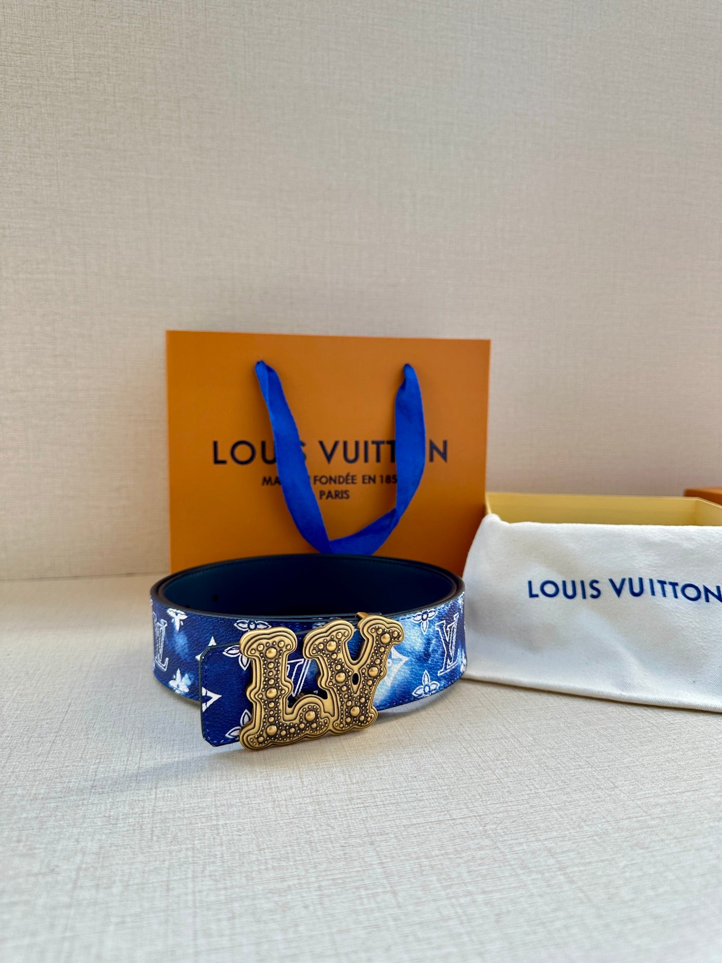 Louis Vuitton belt with blue monogram print, gold-tone ornate buckle, and dark backing.