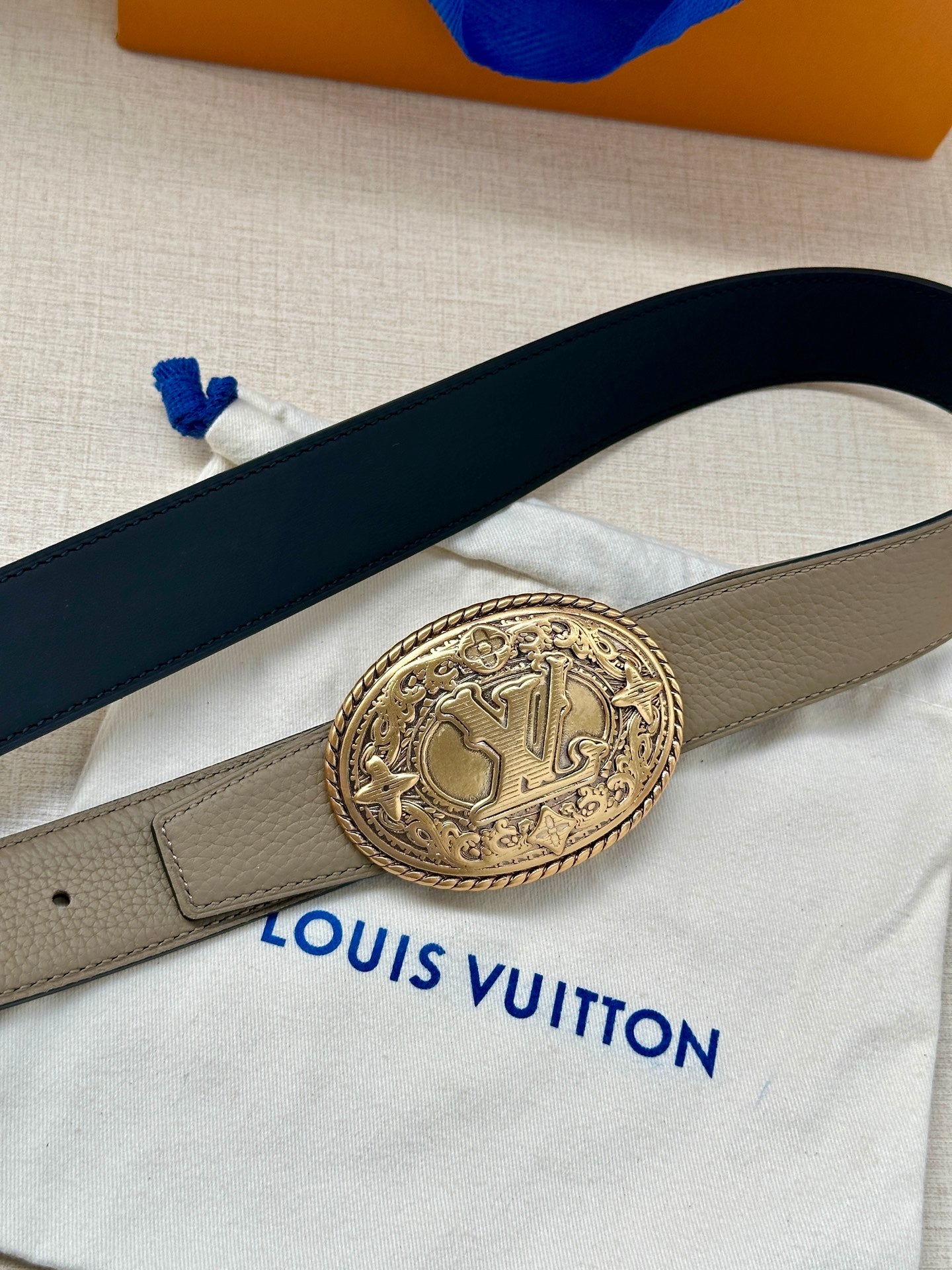 Louis Vuitton belt close-up, beige strap with oval emblem buckle