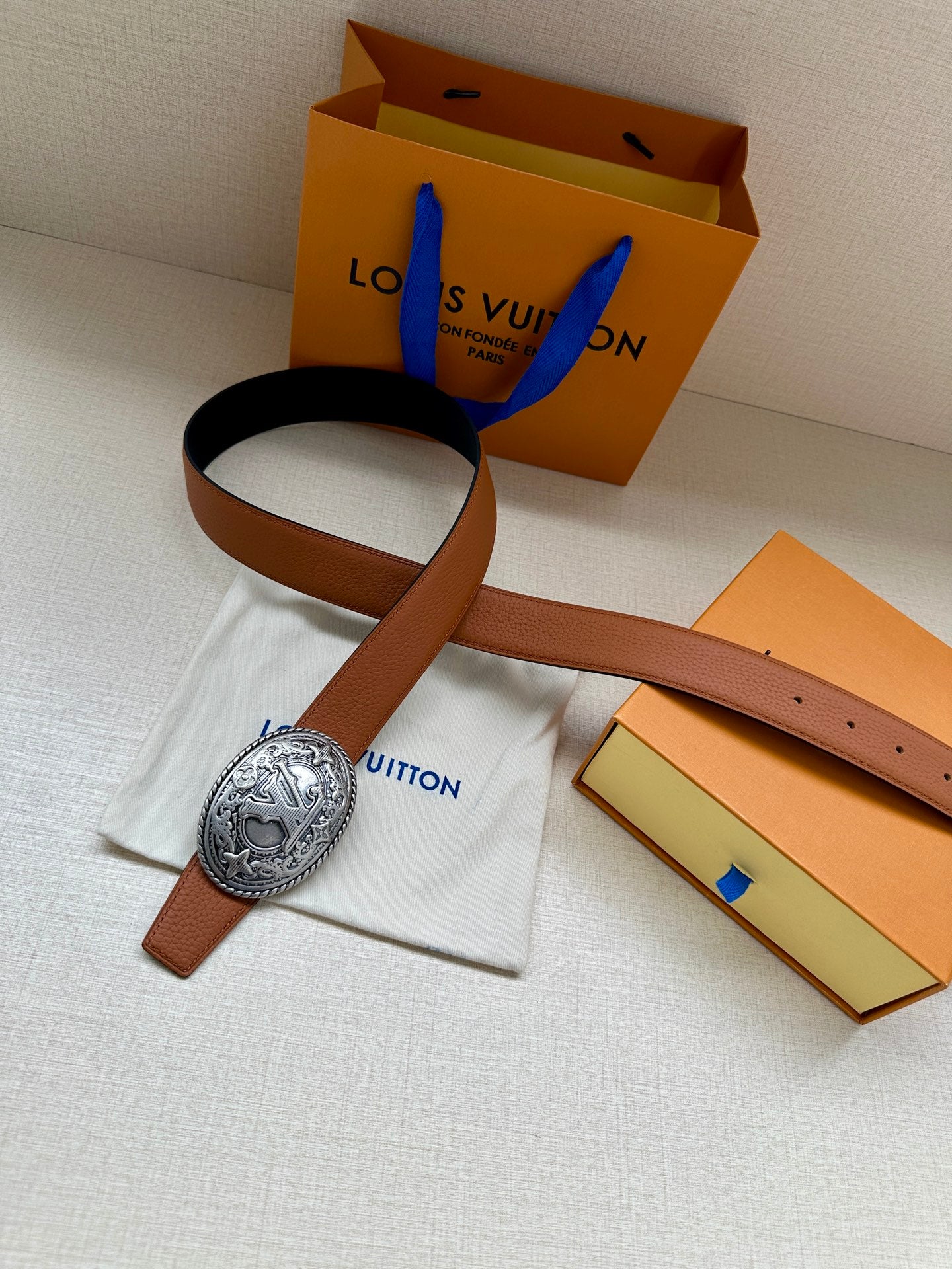 Brown leather belt with silver-tone oval buckle and navy accent strap