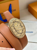 Tan leather belt with textured grain and gold-tone oval logo buckle