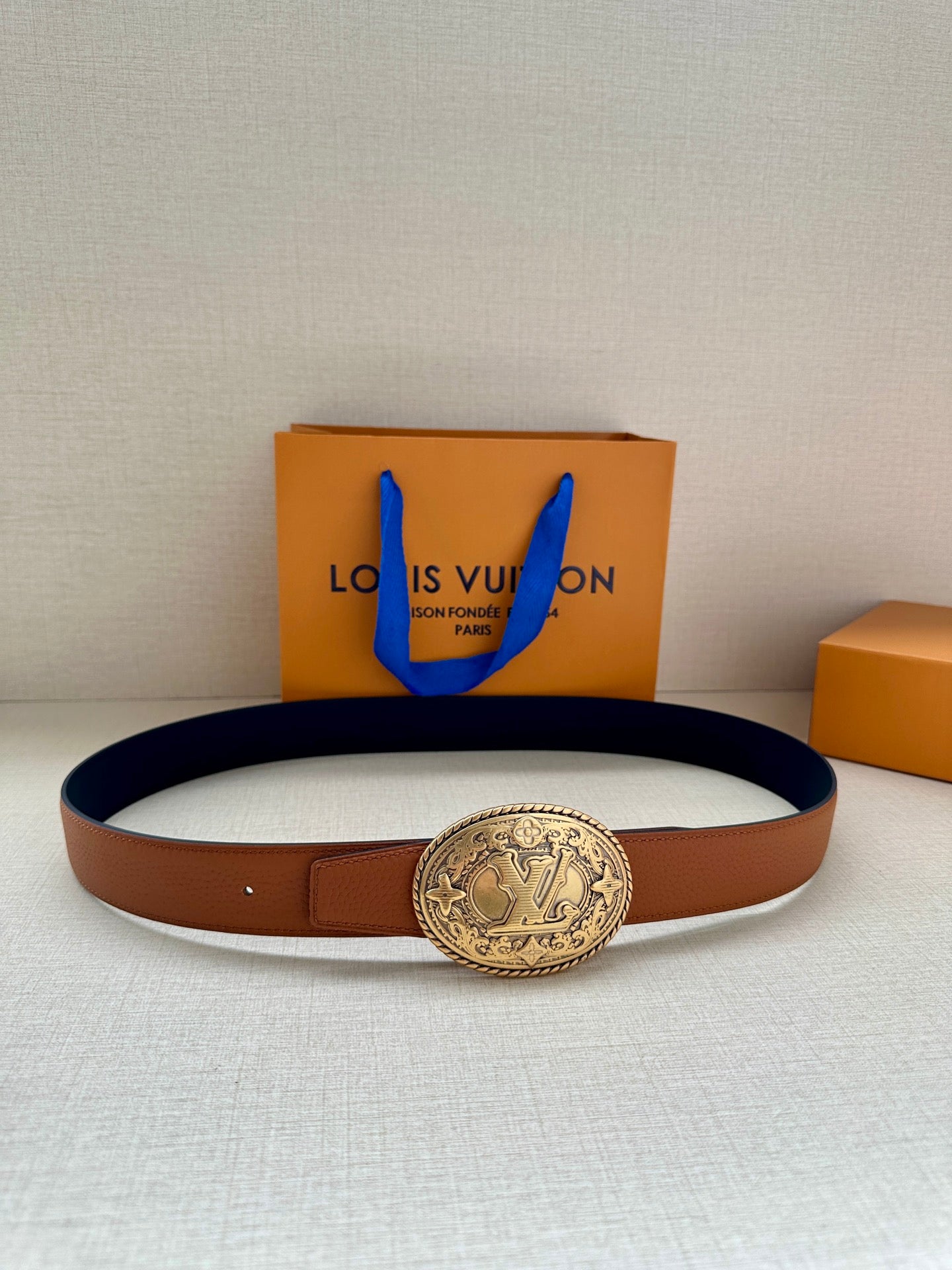 Brown leather belt with gold-tone oval logo buckle