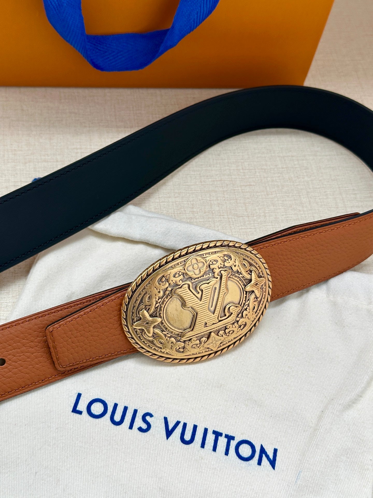 Brown and navy leather belt with silver-tone oval logo buckle