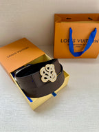 Brown belt with silver monogram buckle inside open box with blue strap ties.