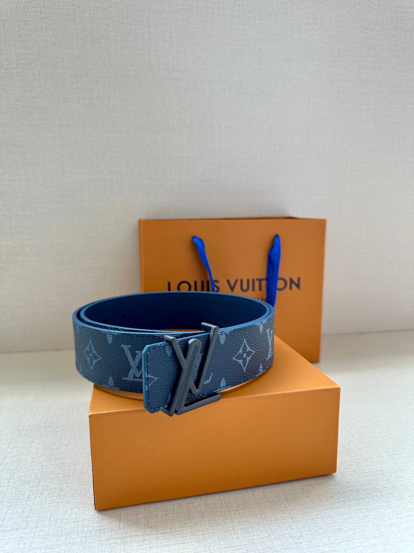 Blue monogram belt with front buckle on tabletop