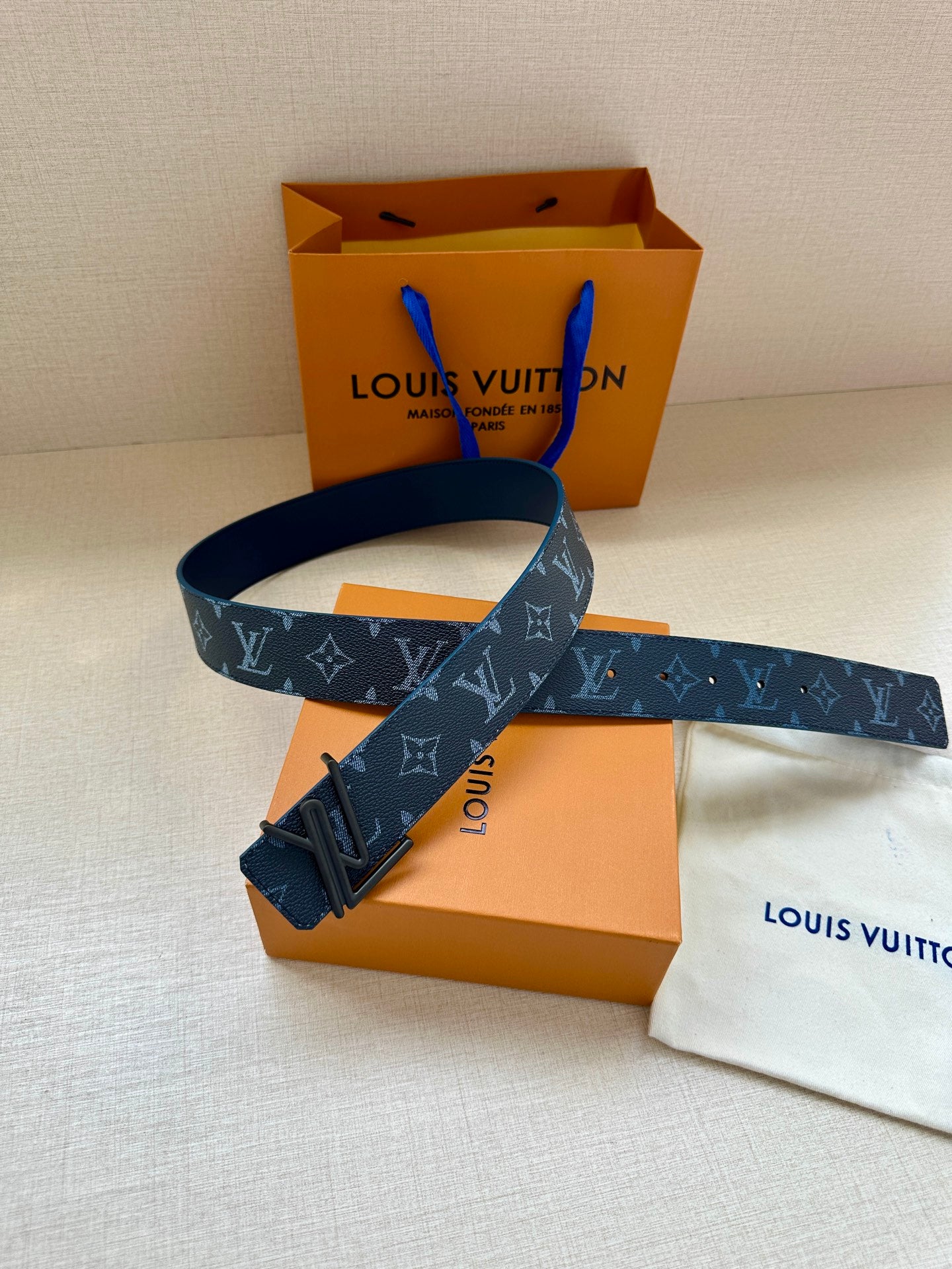 Blue monogram belt with dark buckle, strap laid diagonally