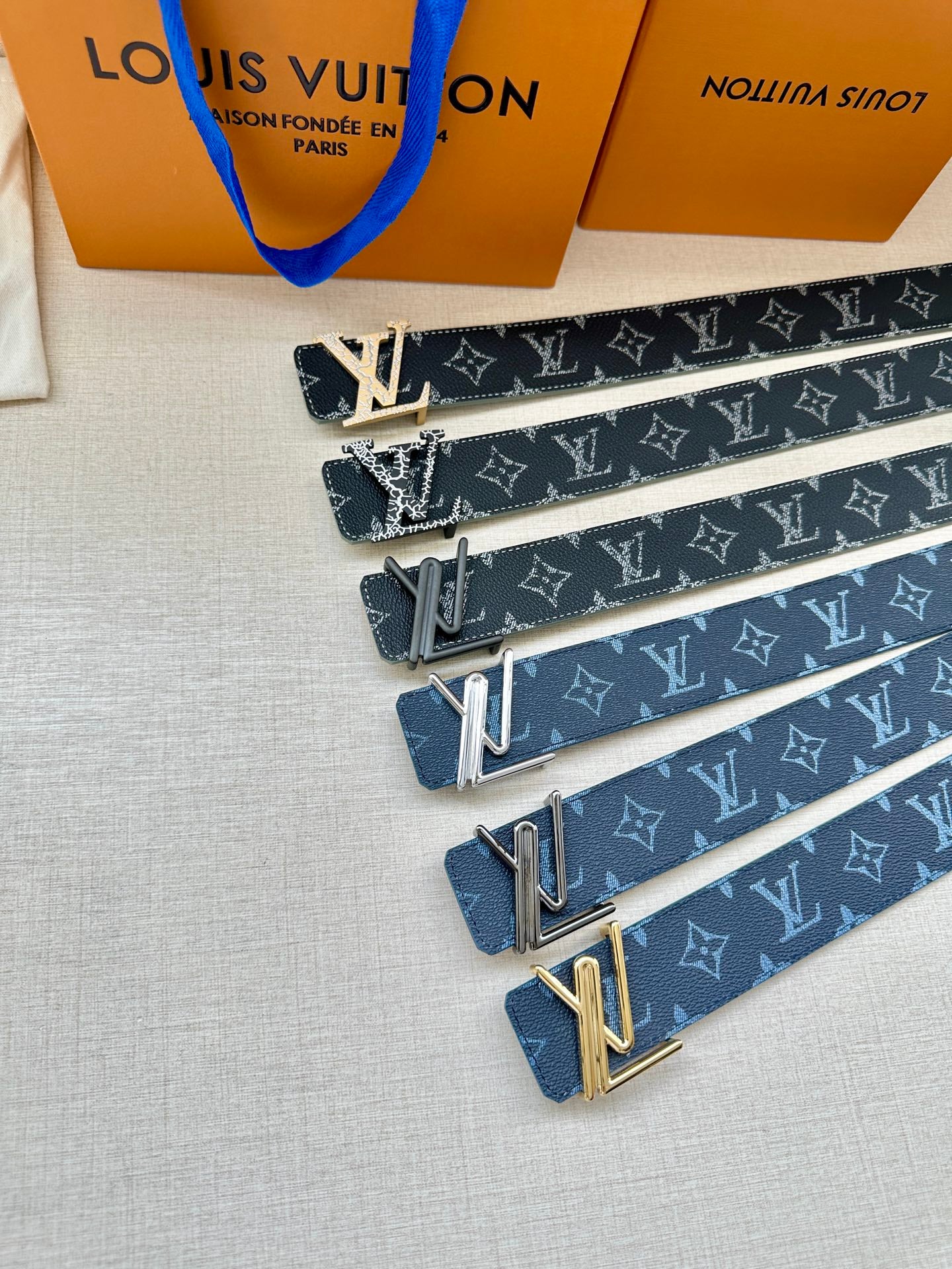 Blue monogram belt set with black, silver, and gold-toned buckles