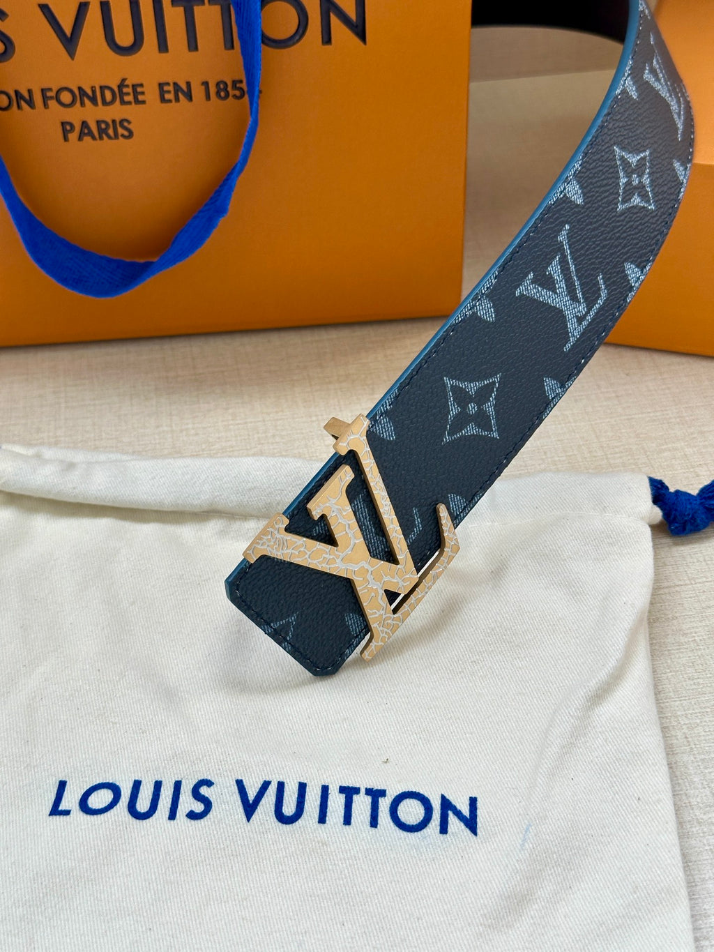 Navy monogram belt with gold-tone LV buckle, close-up