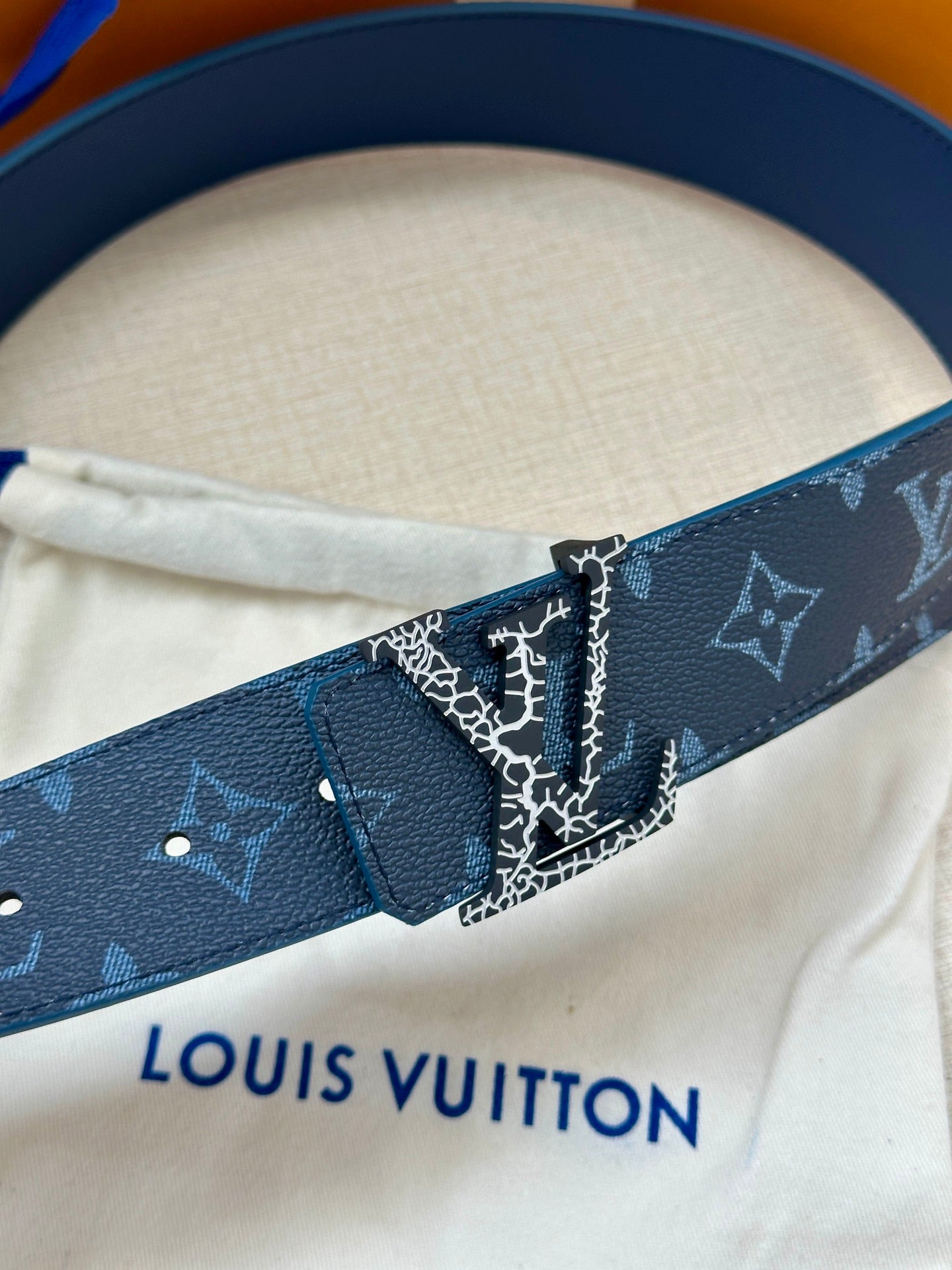 Navy monogram belt strap with silver buckle, close-up