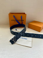 Navy monogram belt with silver buckle and blue stitching, pouch nearby