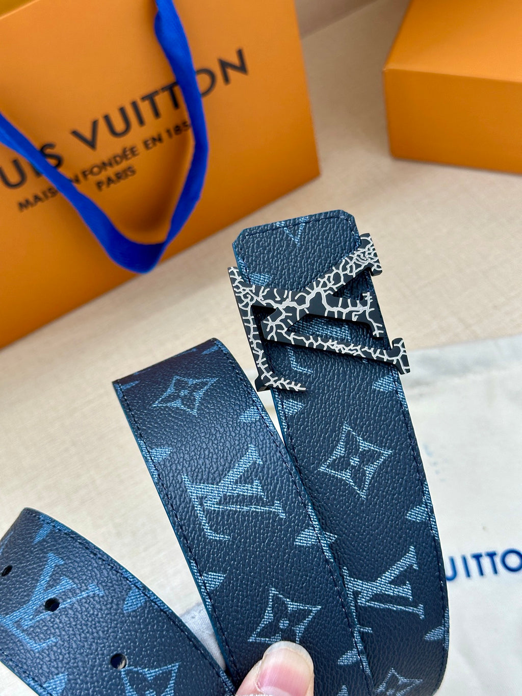 Navy monogram belt with silver buckle clasp, close detail