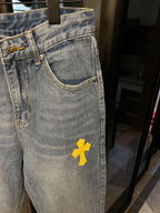 Light-wash denim jeans with yellow cross patch, side pocket area