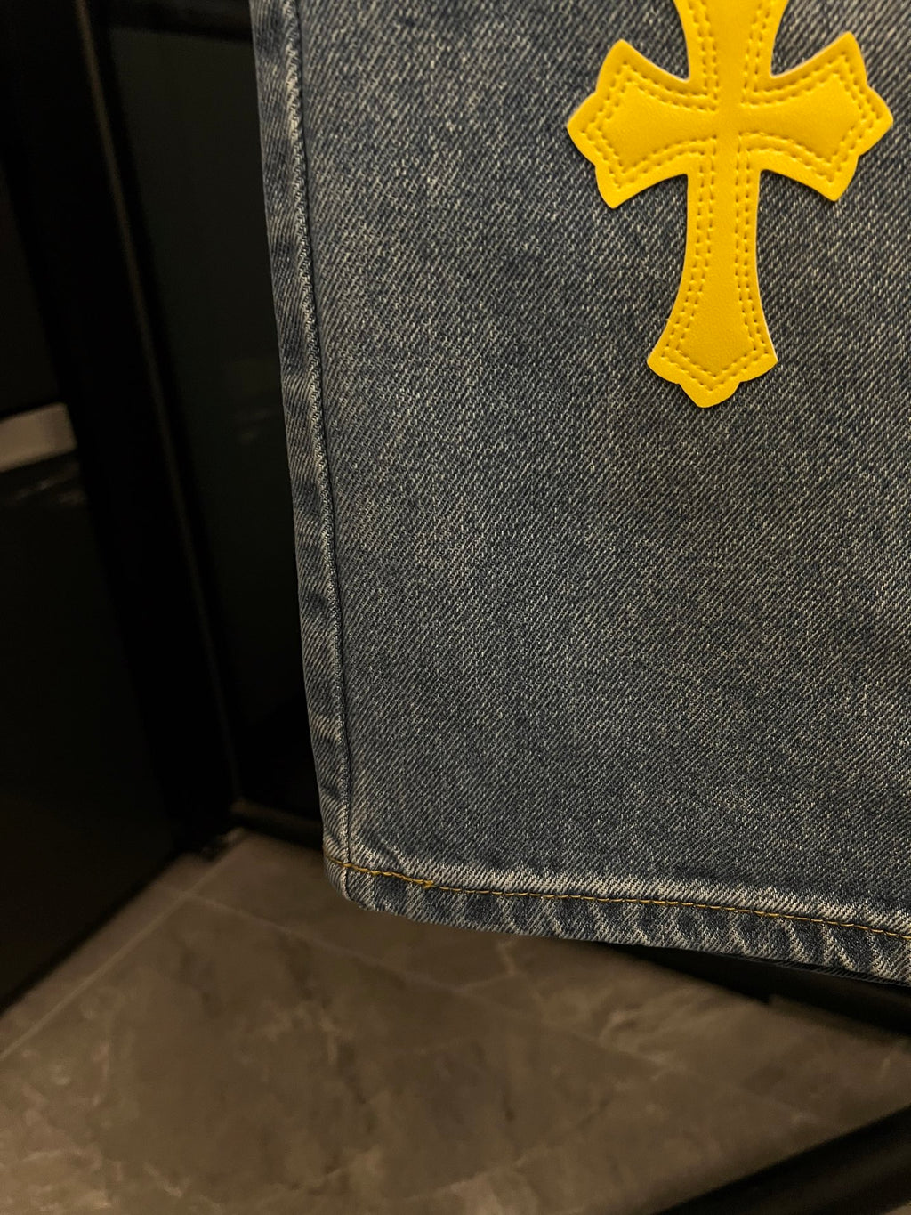Light-wash denim jeans hem with yellow cross patch