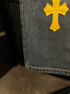 Light-wash denim jeans hem with yellow cross patch